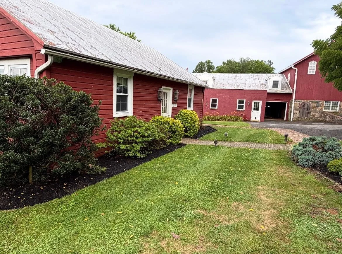 Green lawn, shaped shrubs and tidy beds alongside red garden buildings — Dylan’s Lawn Care